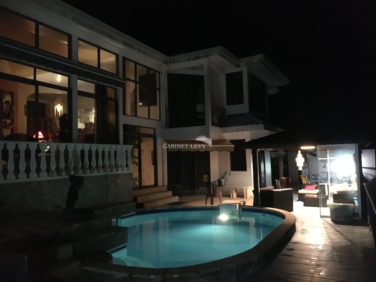 Vue du bâtiment de nuit avec piscine et salon extérieur sur la terrasse